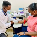 Profissional de saúde aplica uma injeção em um paciente dentro de uma clínica médica.