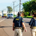 Agentes da Polícia Rodoviária Federal monitoram o tráfego em uma rodovia brasileira durante o dia.