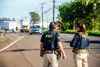 Agentes da Polícia Rodoviária Federal monitoram o tráfego em uma rodovia brasileira durante o dia.