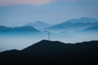 Linhas de transmissão elétrica diante de montanhas ao entardecer em Lima, no Peru.