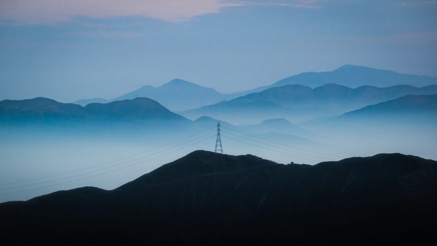 Linhas de transmissão elétrica diante de montanhas ao entardecer em Lima, no Peru.