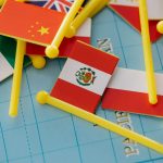 Miniaturas de bandeiras nacionais dispostas sobre um mapa-múndi, simbolizando relações internacionais e diplomacia.