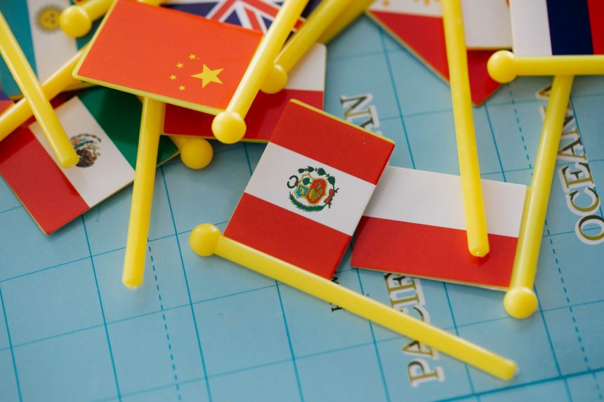 Miniaturas de bandeiras nacionais dispostas sobre um mapa-múndi, simbolizando relações internacionais e diplomacia.