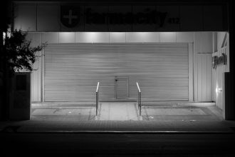 Farmácia fechada em Córdoba, na Argentina, fotografada à noite em preto e branco.