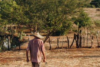 Agricultor caminha por um campo seco em área rural do Brasil.