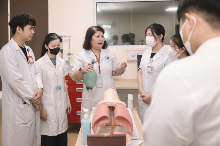 Grupo de estudantes de medicina pratica procedimentos em um manequim durante uma aula de treinamento.
