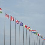 Fileira de bandeiras internacionais hasteadas, representando relações diplomáticas e cooperação entre países.