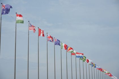 Fileira de bandeiras internacionais hasteadas, representando relações diplomáticas e cooperação entre países.