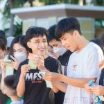 Grupo de jovens sorri e segura ingressos durante um evento ao ar livre.