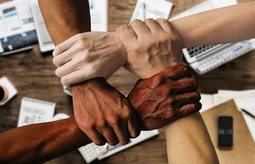 Grupo diverso de profissionais reunido em um ambiente de trabalho, representando colaboração e participação institucional.